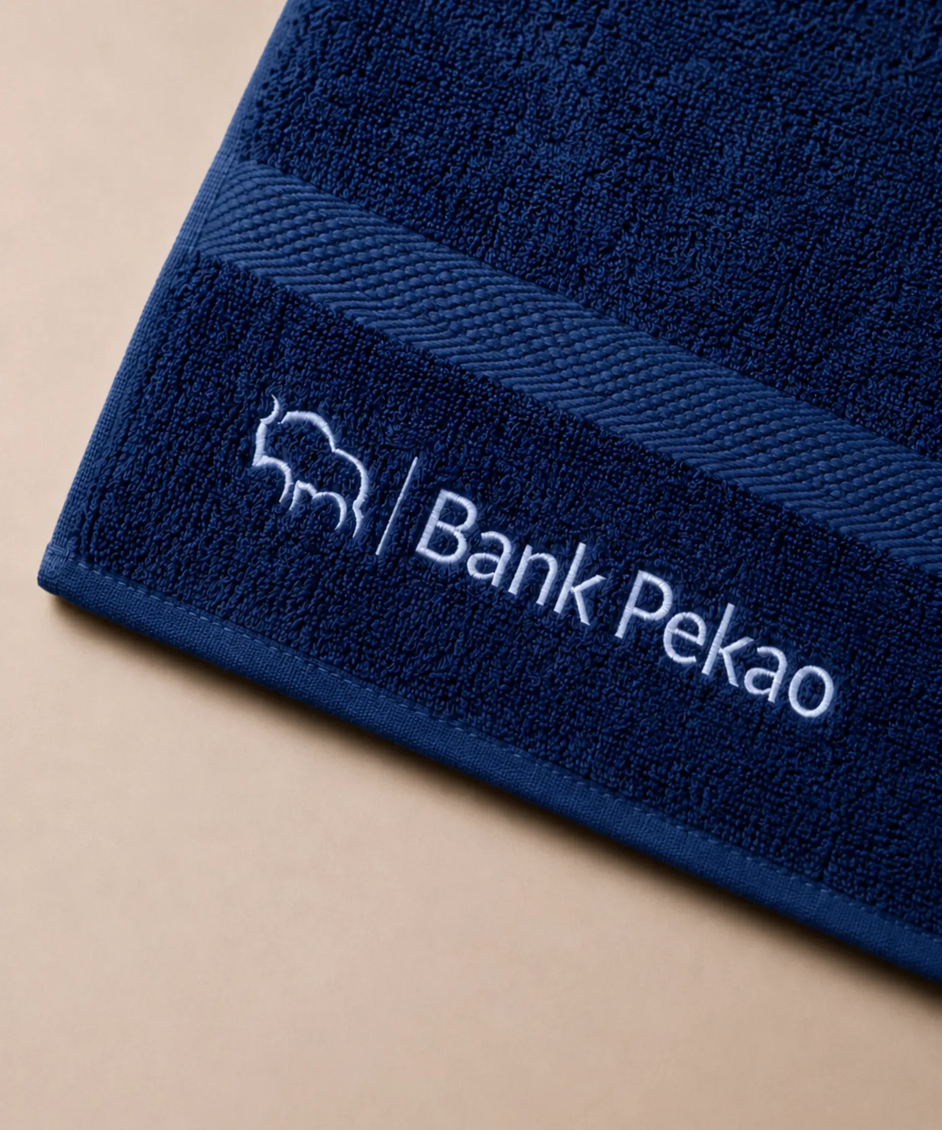 Granatowy ręcznik z haftowanym logo wykonany z miękkiej tkaniny frotte
